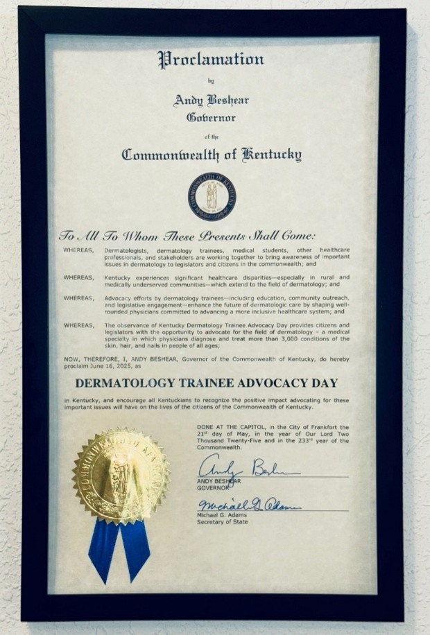 Framed official proclamation from the Governor of Kentucky declaring “Dermatology Trainee Advocacy Day,” featuring the state seal, formal text, signatures, and a gold embossed ribbon.